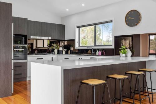ビンセンチアにあるIndigo Views - renovated Vincentia beach houseのキッチン(大きな白いカウンター、スツール付)