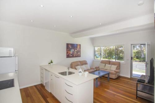 a kitchen with a sink and a living room at Harbour Breeze - apartment in Ulladulla in Ulladulla