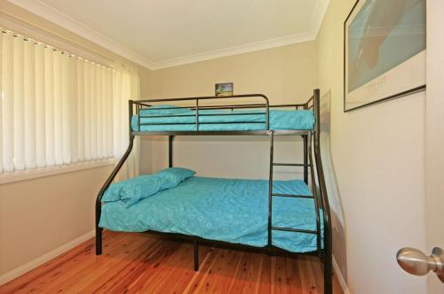 two bunk beds with blue sheets in a room at Bring the Dog, Boat and Family - lakeside escape in Burrill Lake