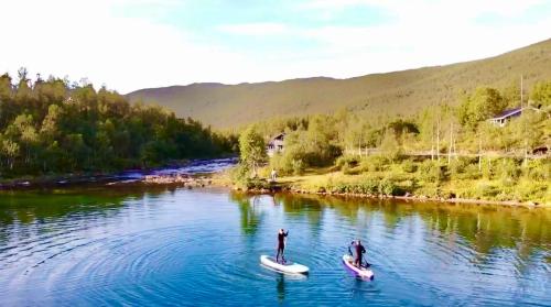 two people are on kayaks on a river at Riverfront house with 98 inch TV, ps5 & activities in Narvik