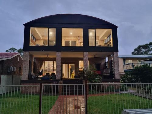 a black house with a large group of windows at Sanctuary Lodge - 5BR waterfront country getaway in Sanctuary Point