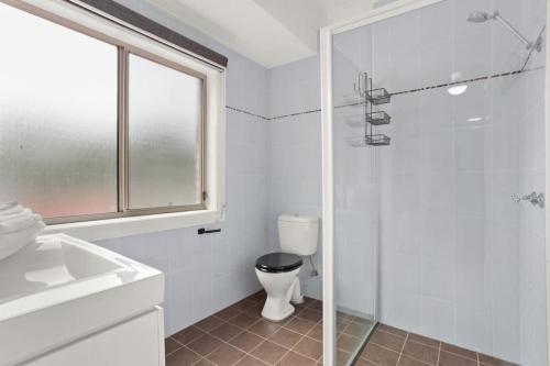 a bathroom with a toilet and a glass shower at Sanctuary Lodge - 5BR waterfront country getaway in Sanctuary Point