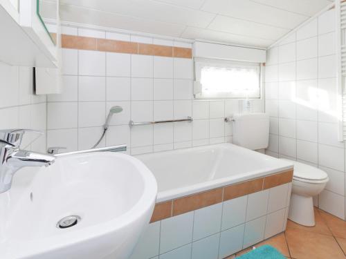 a white bathroom with a sink and a toilet at Ruhiger Bungalow am Hennesee mit Terrasse 