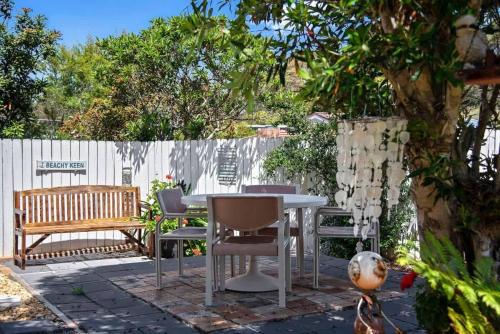 a patio with a table and chairs and a fence at Mollymook Beach Haven - near ocean & golf course in Mollymook