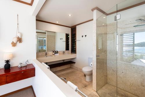 a bathroom with a shower and a sink and a toilet at Alang Alang on Hamilton Island by HIHA in Hamilton Island