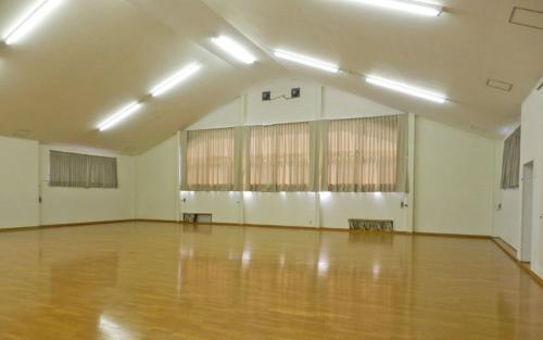 a large room with a wooden floor and windows at トガリハイランド白樺 in Iiyama