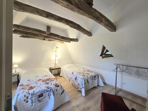 Gîte de charme à Limeuil avec Internet et parking - FR-1-616-497 في Limeuil: سريرين في غرفة مع عوارض خشبية