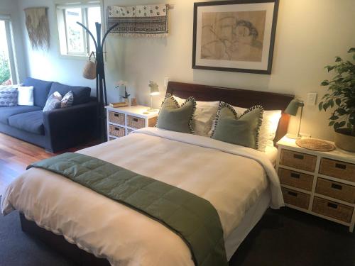 a bedroom with a large bed and a couch at Sweet As Suite in Auckland
