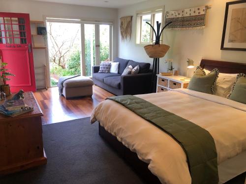a bedroom with a bed and a living room at Sweet As Suite in Auckland