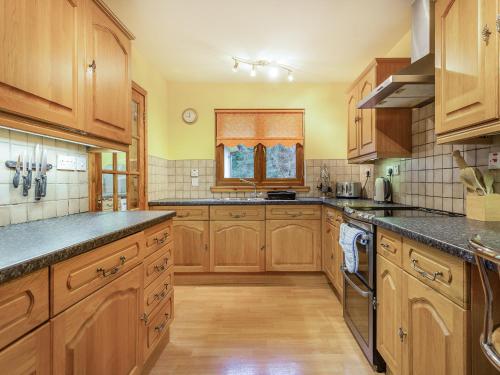 a large kitchen with wooden cabinets and a window at Bidean Lodge in Glencoe