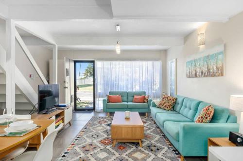 a living room with a blue couch and a tv at Ocean Cove - cosy retreat steps from beach & cafes in Mollymook