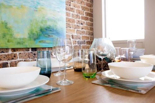 a wooden table with wine glasses and plates on it at Ocean Cove - cosy retreat steps from beach & cafes in Mollymook
