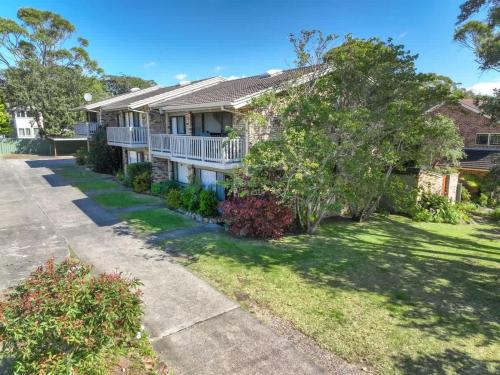 a house with a yard with a driveway at Ocean Cove - cosy retreat steps from beach & cafes in Mollymook