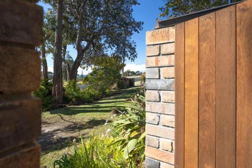 a brick wall with a wooden gate in a yard at Ocean Cove - cosy retreat steps from beach & cafes in Mollymook