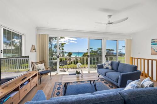a living room with a blue couch and a table at Seaside Beach House in Burrill Lake