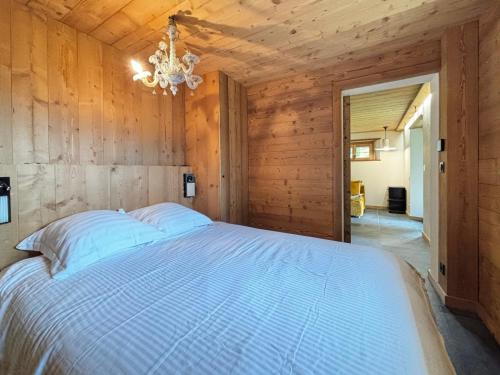 1 dormitorio con 1 cama blanca en una pared de madera en Chalet confortable au village, 10 pers, vue et wifi - FR-1-505-232, en Notre-Dame-de-Bellecombe