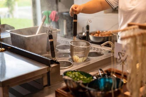 a person preparing food on a stove in a kitchen at 上海浦东机场华美达安可酒店-免费提供24小时浦东机场班车十分钟到达候机楼出发层 in Shanghai
