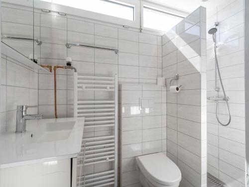 a white bathroom with a toilet and a sink at Bungalow in Julianadorp near Sandy Beach in De Zandloper