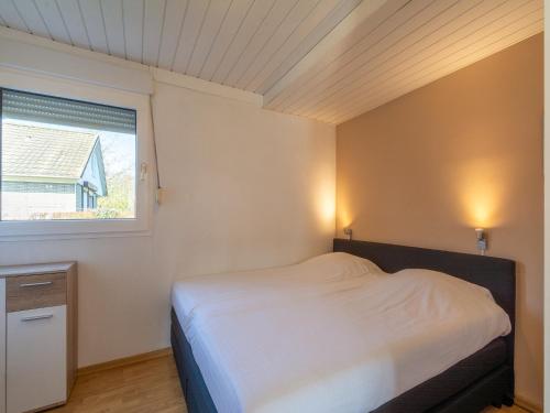 a small bedroom with a bed and a window at Bungalow in Julianadorp near Sandy Beach in De Zandloper