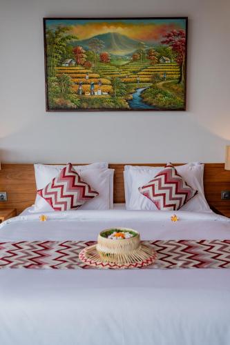 a bed with a table on it with a picture on the wall at Greha Natha Villa Ubud in Ubud