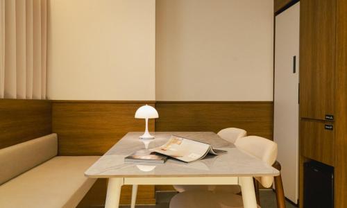 a table with a lamp and chairs in a room at Brown Dot Hotel Andong Taehwa in Andong