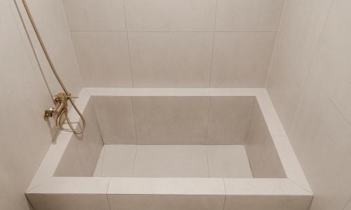 a bathroom with a shower with a white tile floor at Brown Dot Hotel Andong Taehwa in Andong