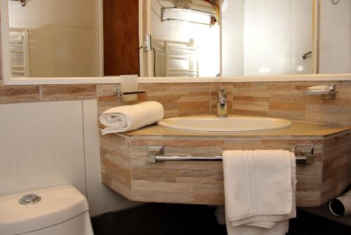 a bathroom with a sink and a toilet and a mirror at Hotel Rucaitue in Osorno