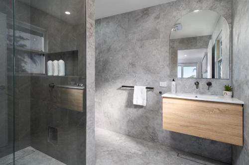 a bathroom with a sink and a shower and a mirror at Aarini Cottage - The Ultimate Beachside Escape! in Macmasters Beach