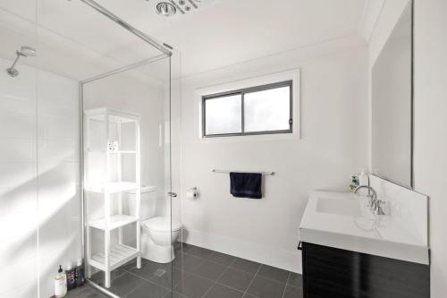a bathroom with a shower and a toilet and a sink at Aloha Kioloa in Kioloa