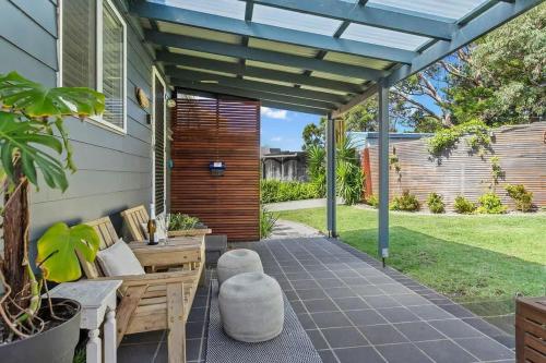 a patio with a bench and a pergola at All Decked Out in Kioloa