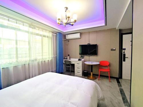 XialuozhaiにあるYiwu Jun'an Hotelのベッド、机、テレビのある寝室