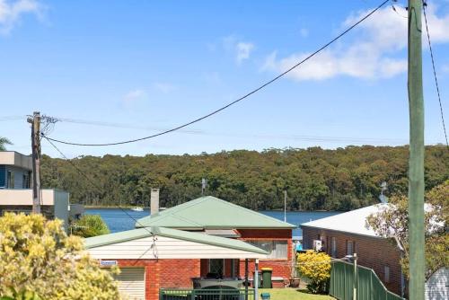 a house with a green roof with a lake in the background at Barker Retreat in Burrill Lake