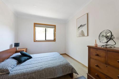 a bedroom with a bed and a dresser and a window at Barker Retreat in Burrill Lake