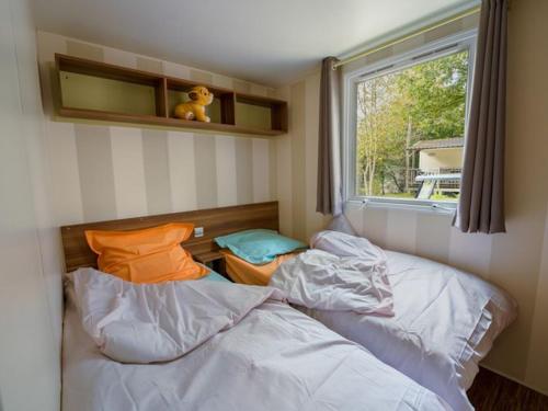 two beds in a small room with a window at Mobil home moderne avec terrasse pour 4 personnes - API-1-52-468 in Granges-Aumontzey