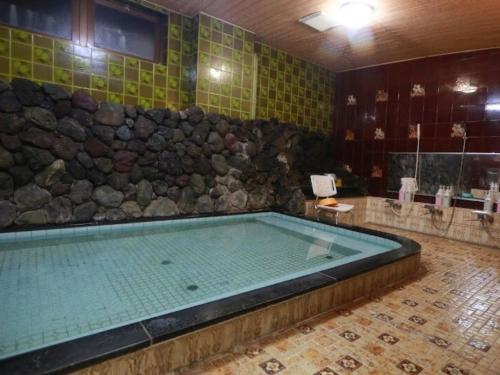 a large tub in a bathroom with a stone wall at Takao Kanko Hotel in Kyoto