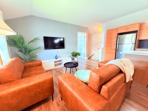 a living room with two orange couches and a flat screen tv at Le Central Fonctionnel Confort - 2CH in Quebec City