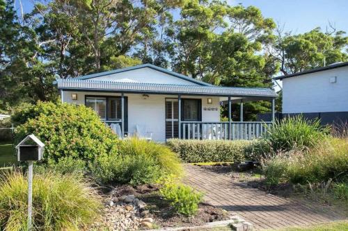 a small white house with a porch at Bawley Beach Bungalow in Bawley Point