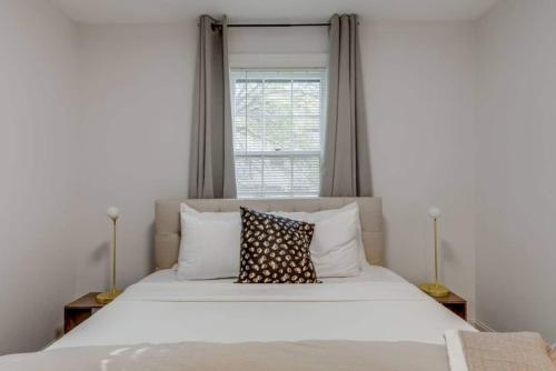 a bedroom with a large white bed with a window at Nashville's Primrose Cottage In Hip Belmont Area in Nashville