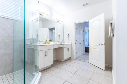 une salle de bain avec deux lavabos et une douche en verre dans l'établissement Elsa's Enchanting Escape just 15 minutes to Disney, à Kissimmee