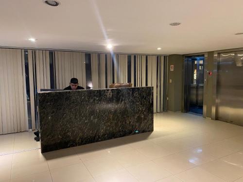 a man sitting at a counter in a lobby at Moderno departamento céntrico, con piscina-Barrio Norte in San Miguel de Tucumán