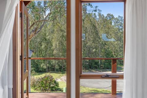 an open glass door with a view of a yard at The Beach Haven in Bawley Point