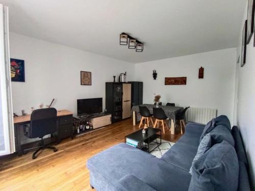 a living room with a blue couch and a table at Charmant appartement avec jardin, barbecue et Netflix in Méry-sur-Oise