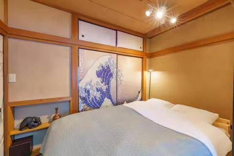 a bedroom with a white bed and a painting of a tsunami at Oc4 お花茶屋駅から4分の戸建て in Tokyo