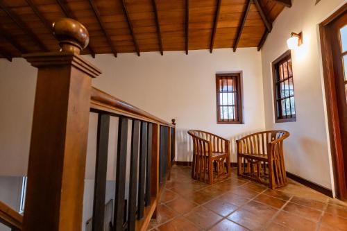 a hallway with two chairs and a wooden staircase at Ceylon Holiday Homes in Kandy