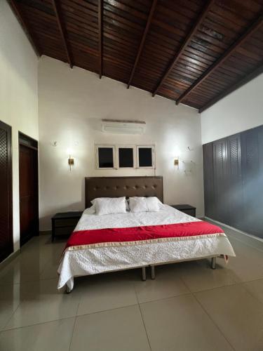 a bedroom with a large bed with a red blanket at Hotel Plaza Colonial in Valledupar