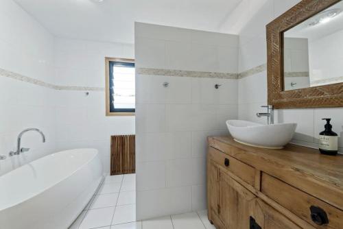 a bathroom with a tub and a sink and a mirror at Narrawallee Oasis in Narrawallee