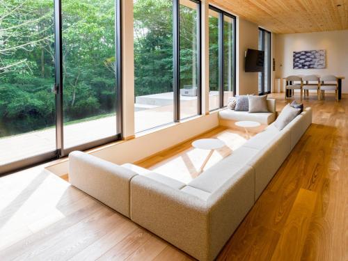 a living room with a large couch and large windows at Rakuten STAY VILLA Aso Kurokawa -104 1LDK Capacity of 6 persons in Minamioguni