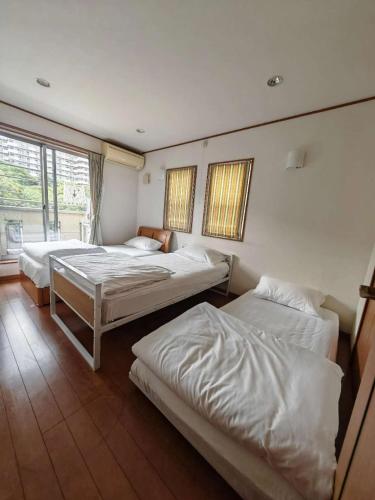 a bedroom with two beds and two windows at スペース海浜幕張ハウス in Chiba