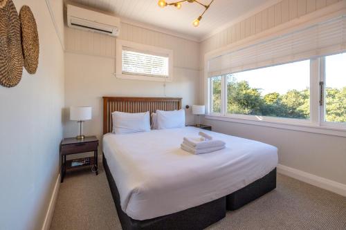 a bedroom with a large white bed with a window at Island Villa- Stay Waiheke in Oneroa