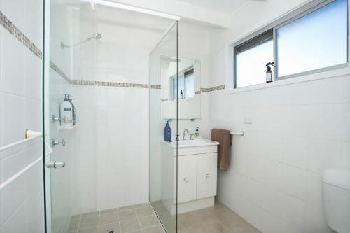 a bathroom with a glass shower and a sink at MeNo's at Bawley in Bawley Point